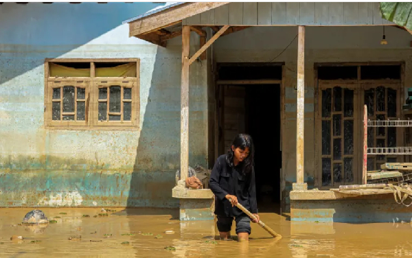 A girl walks through mud in front of her house in a flood-affected area in a province in  Indonesia
