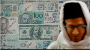 A man stands in front of specimen banknotes