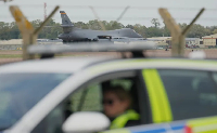 A B1 bomber prepares to take off as police officers man a checkpoint near RAF Fairford airbase