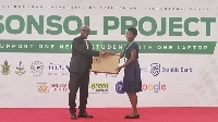 Stephen Amoah presenting laptop to a brilliant student