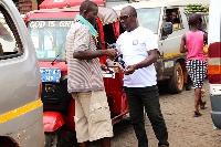 A member of the Obuasi Area Pentecost Men's Ministry interacting with a bus worker