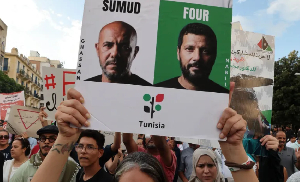 Tunisian protesters hold a banner denouncing the criminalisation of solidarity with the Palestinians