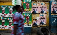 A woman walks past election posters of All Progressives Congress (APC) party candidates