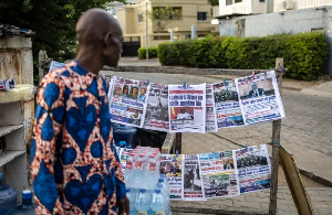 A vendor looks at newspapers displayed on a stall, on Dec. 8, 2025, a day after the failed coup