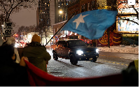 A demonstrator waves a flag of Somalia as a vehicle passes by a rally in protest