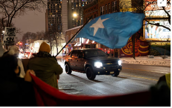 A demonstrator waves a flag of Somalia as a vehicle passes by a rally in protest