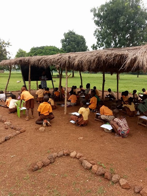 The pupils seated on the ground, taking their end of year examinations