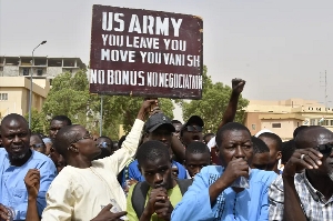 A man holds up a sign demanding that soldiers from the United States Army leave