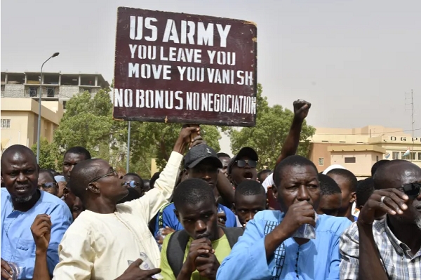 A man holds up a sign demanding that soldiers from the United States Army leave