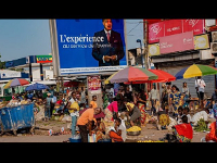 An election poster featuring President Denis Sassou N'Guesso stands over a market