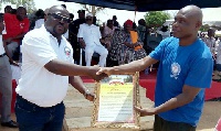 Peter Ayimbisa presenting a citation to a worker