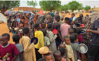 Women and children queue to receive food being distributed in al-Mohayra camp for displaced people