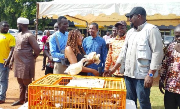 John Dumelo (R) presenting some of the birds to a female farmer