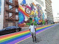 Moh Awudu poses beside the 60-foot historic mural in Newark
