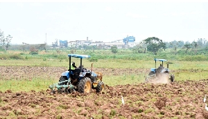 Tractors ploughing a farmland