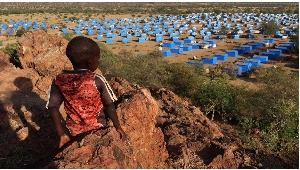 A boy sits atop a hill overlooking a refugee camp near the Chad-Sudan border on November 9, 2023