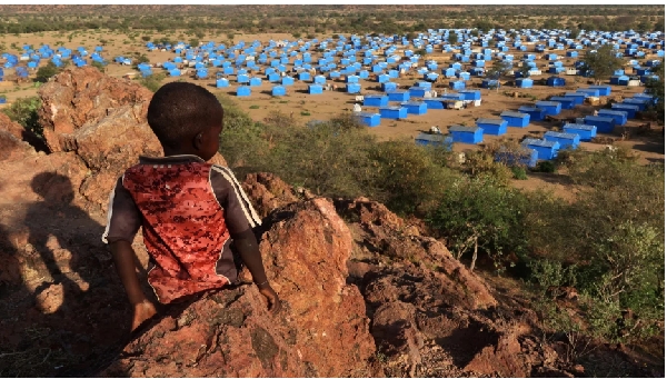 A boy sits atop a hill overlooking a refugee camp near the Chad-Sudan border on November 9, 2023