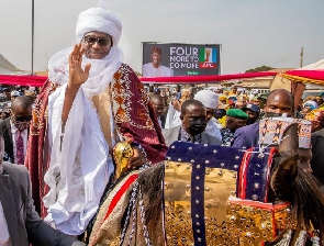 The billboard in the background shows the candidate and the slogan