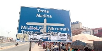 A photo of a road sign defaced with posters and notices
