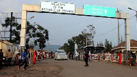 People walk past the Congo side of the Poids Lourd checkpoint at the border between Congo and Rwanda