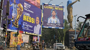Commuters pass Messi posters and a veiled statue in Kolkata, ahead of his visit