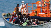 A group of migrants wait to disembark from a wooden boat after being rescued