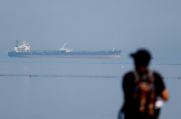 A tourist watches the MT Desert Kite oil tanker carrying Russian oil at Narara Marine National Park