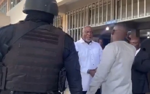 Hopeson Adorye (in white shirt) facing off with an officer at the police station