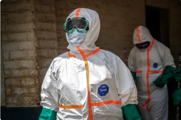 Health workers wearing protective equipment gather to disinfect isolation area for Ebola patients