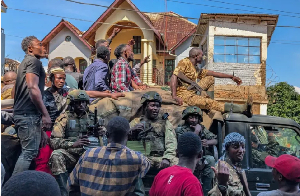 Residents walk next to a vehicle with M23 fighters on in Bukavu