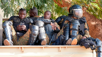 Burkina Faso Police sit outside the courtroom where 14 people, stand trial for the murder of leader