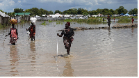Women wade through flood waters after the River Nile broke the dykes in Pibor