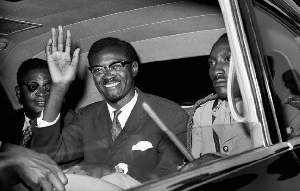 Congo's PM Patrice Lumumba waves as he sits in car for the drive from Idlewild Airport, July 24,1960