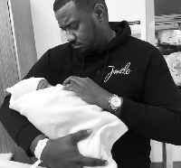 Actor John Dumelo holding his first child in the hand