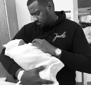 Actor John Dumelo holding his first child in the hand