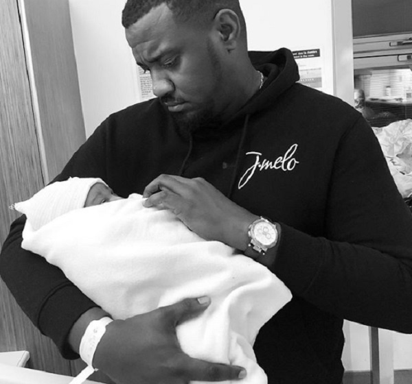 Actor John Dumelo holding his first child in the hand