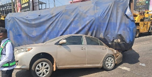 A picture from the accident scene shows a truck covered with blue tarpaulin and a saloon car