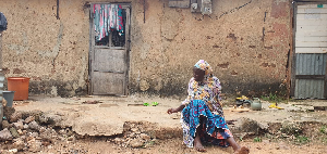 The 80-year-old Nma Kombozie Jakare sitting in front of the dilapidated house