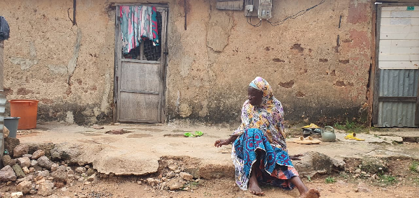 The 80-year-old Nma Kombozie Jakare sitting in front of the dilapidated house