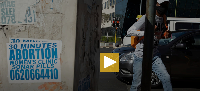 A pedestrian walks past a sign pasted on a sidewalk in Johannesburg, South Africa