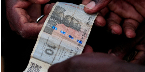 A trader receives a ten ZiG note from a customer at a vegetable market in Harare, Zimbabwe