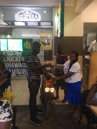 One of the winners receiving a scooter from a staff Basilissa