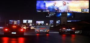 Vehicles drive past brightly lit billboards, amid rising concerns about the impact of big billboard