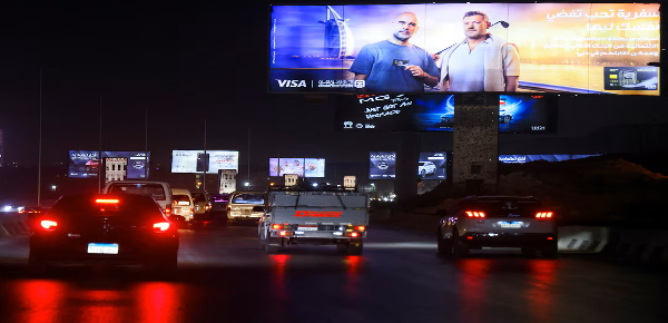 Vehicles drive past brightly lit billboards, amid rising concerns about the impact of big billboard
