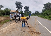 A galamseyer removing mud from a road