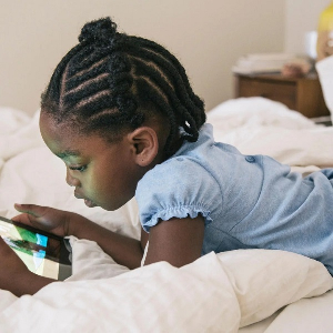 A picture of a child holding a phone and watching the screen