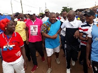 Nana B (M) and Abronye DC holding their hands and flanked by some participants during a health walk