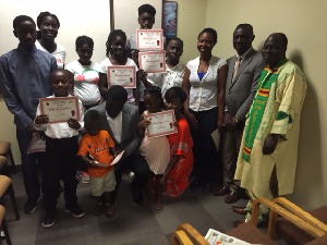 Kids proudly display their certificates of participation with author, Francis Atta and executives as