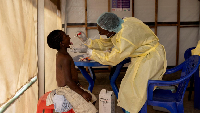 Christian Musema, a laboratory nurse, takes a sample from a child declared a suspected case