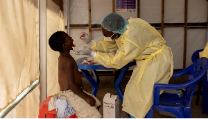 Christian Musema, a laboratory nurse, takes a sample from a child declared a suspected case